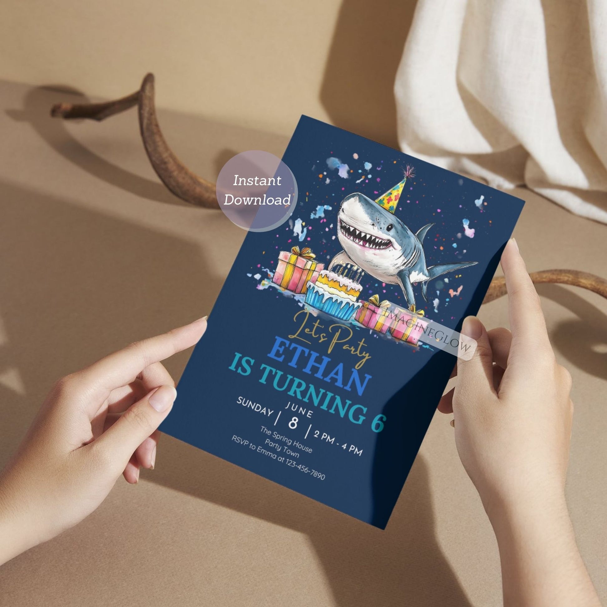 Person holding a shark-themed birthday party invitation card with colorful graphics