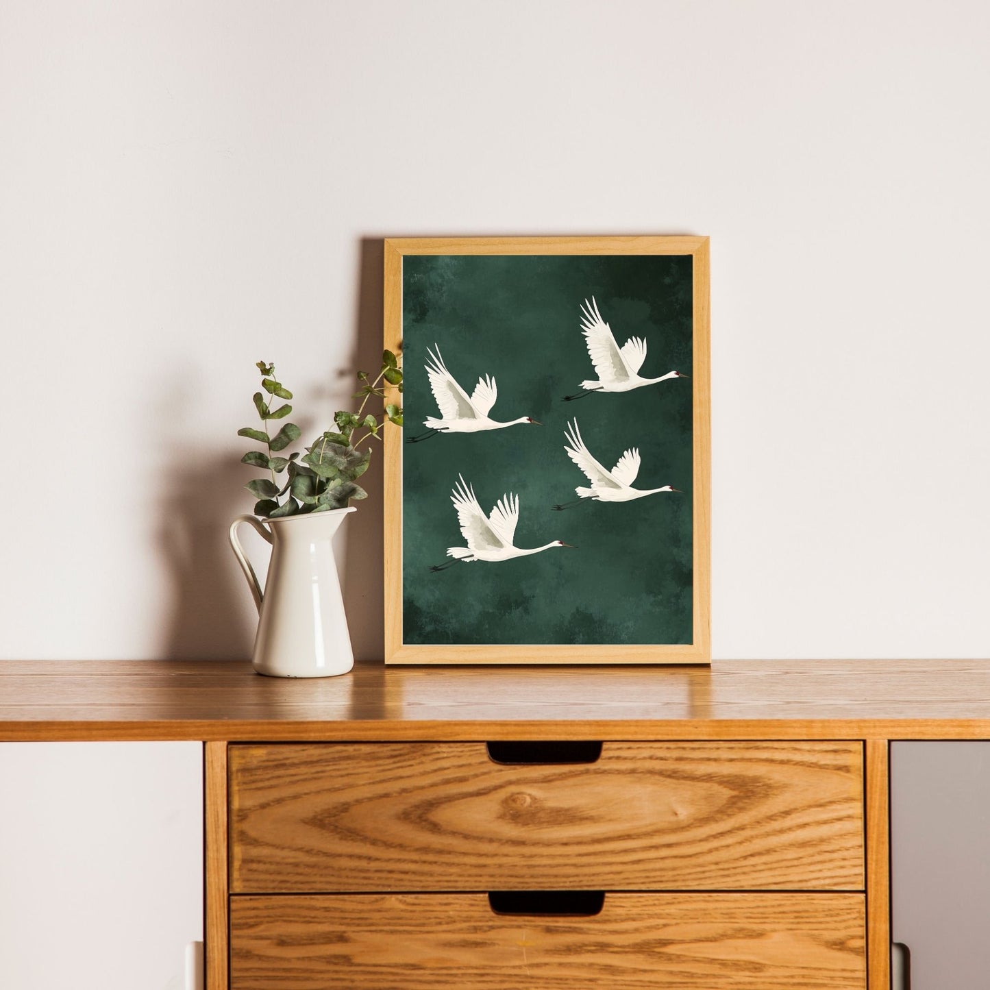 Green wall art featuring Japanese cranes in motion.