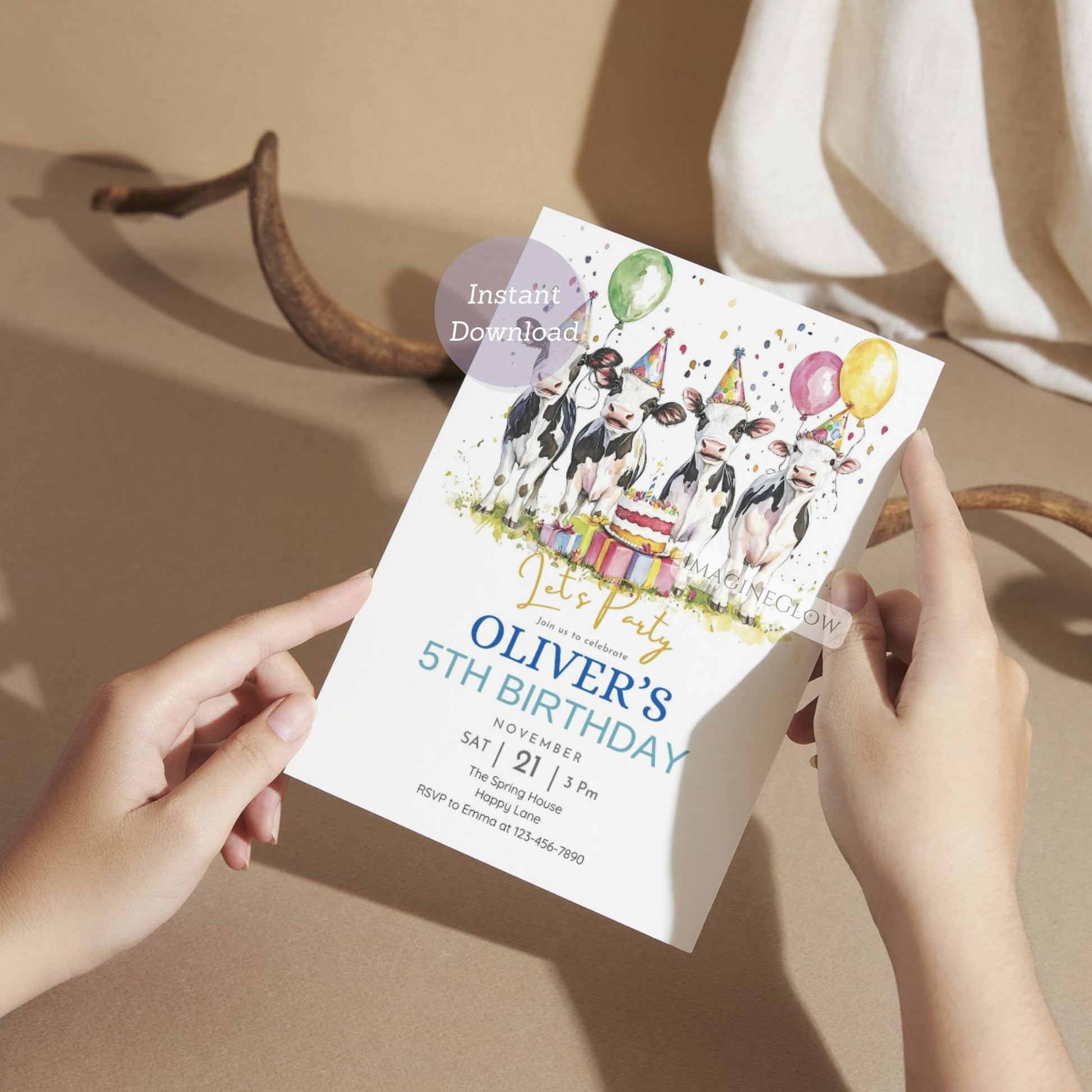 Person holding a birthday invitation card with cows and balloons on a beige background