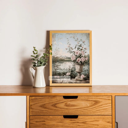 Antique-style wall art of a tranquil lake with wildflowers.
