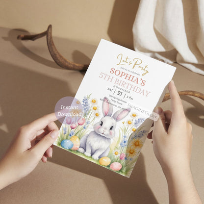 Birthday invitation card with a rabbit and Easter eggs held by hands on a neutral background